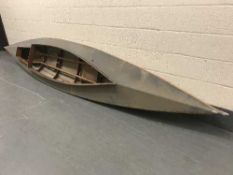 A canvas and wooden framed kayak with two paddles