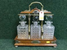 An oak and brass mounted three decanter tantullus