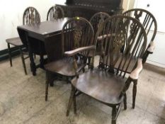 An oak drop leaf table and six wheel back chairs