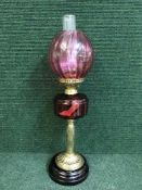 A brass and cranberry glass oil lamp