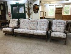 An oak framed three seater settee and matching pair of armchairs