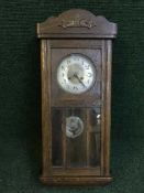 An oak cased wall clock with silvered dial