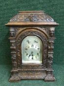 A carved oak chiming bracket clock with silvered dial
