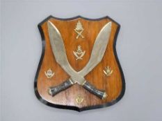 A pair of decorative Kukri knives mounted on a shield plaque.