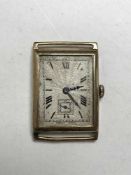 A vintage oblong gold watch, missing glass but ticking.