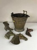 A brass coal bucket containing brass horse head figures,