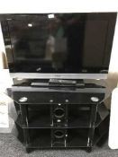 A Sony Bravia 32 inch LCD TV with remote on glass three tier stand