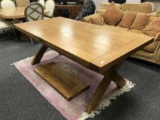 A solid oak extending dining table on X-frame support