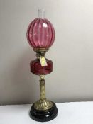 A Victorian cranberry glass oil lamp on gilt brass column