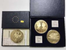 A boxed Windsor Mint Jumbo Gold Dream gold plated coin and two other similar