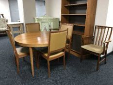 A mid 20th century extending teak dining table and five chairs together with a teak bookcase of
