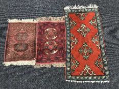 Two fringed woolen prayer mats and a fringed rug on red ground