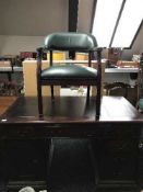 A twin pedestal desk inset three leather panels and an armchair upholstered in green buttoned