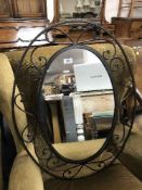 A contemporary oval wrought iron framed mirror