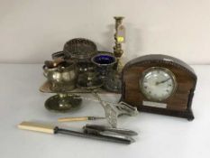 A tray of early 20th century eight day mantel clock, brass candlesticks, cutlery,
