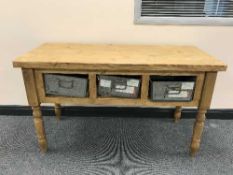 A reclaimed pine side table with three metal drawers