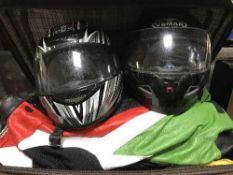 A suitcase of motor bike leathers and two motor bike helmets