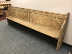 A late Victorian pine pew, 272 cm length.
