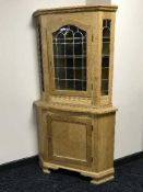A blonde oak leaded door corner cabinet