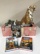 A box of assorted books and a large figure of a leopard