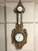 An early twentieth century carved light oak barometer / clock / thermometer