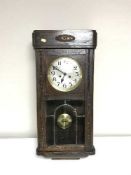 An early 20th century oak wall clock with silvered dial