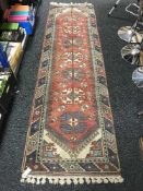 A fringed Turkish woolen runner on red ground