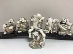 A set of six oriental carved figures on graduated wooden stands
