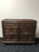 A heavily carved oak bookcase base