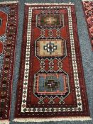 A geometric designed rug on red ground 187 cm x 87 cm