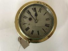 A circular brass ship's wall clock