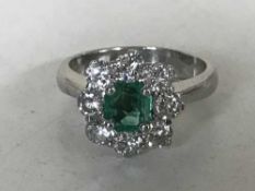 An 18ct white gold diamond and emerald cluster ring