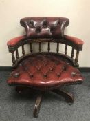 A burgundy leather revolving desk chair