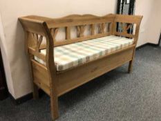 A pine storage bench with tartan cushion