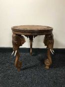 A heavily carved Eastern occasional table on elephant legs