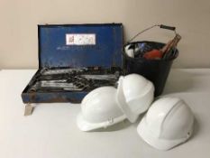 A cased Heyco tool kit, bench grinder, hard hats, hand tools, oil can,