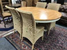 An extending dining room table with four Lloyd Loom dining chairs