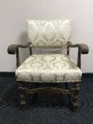 A carved oak armchair in cream brocade