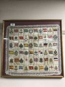 A collection of cigarette silks - military flags and badges - in frame