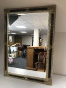 A decorative black and gilt framed bevelled overmantel mirror