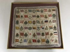A collection of cigarette silks - military flags and badges - in frame