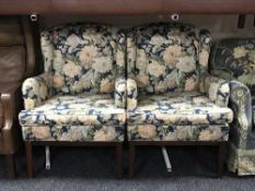 A pair of floral wing backed armchairs on mahogany legs
