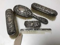 A five piece silver backed dressing table brush set