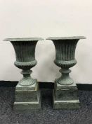 A pair of cast metal garden urns on stands