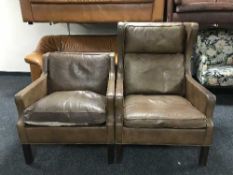 A pair of brown leather armchairs
