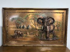 A framed copper relief plaque depicting elephants signed Gastone together with a mahogany leather