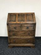 An oak linen folded writing bureau fitted with three drawers