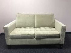 A two seater settee upholstered in green buttoned dralon