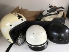 A box of two early 20th century motor bike racing helmets with one set of goggles,