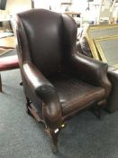A Georgian style brown leather wingback armchair